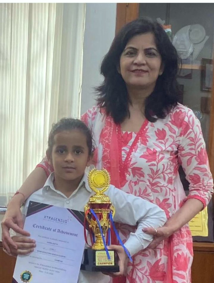 Grade 2 student felicitated by her school principal with her champion trophy